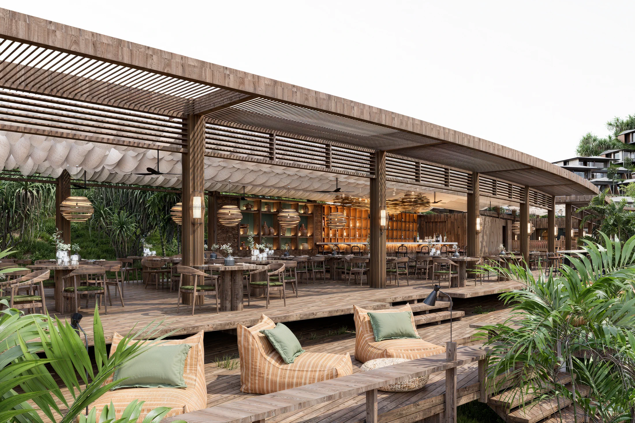Restaurantpaviljoen van AURAH aan de kust met open gevel, loungebanken en tropische beplanting.